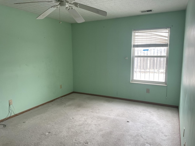 empty room with ceiling fan, a textured ceiling, and light carpet