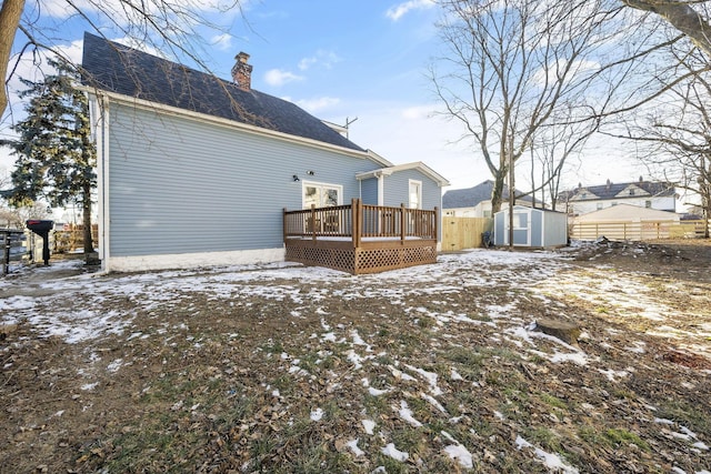 snow covered house with a storage unit and a deck