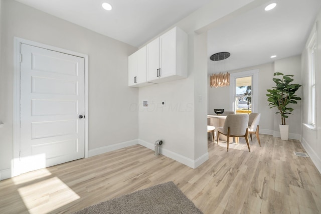 washroom with cabinets, electric dryer hookup, washer hookup, and light hardwood / wood-style flooring