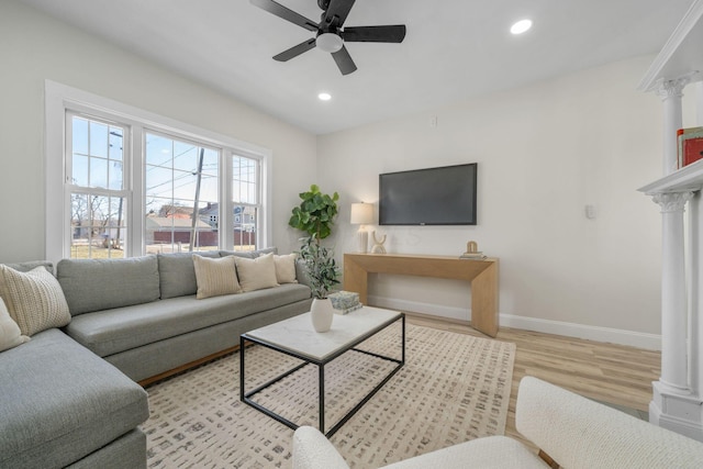 living room featuring light hardwood / wood-style floors, ceiling fan, and ornate columns