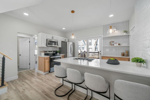 kitchen featuring sink, appliances with stainless steel finishes, hanging light fixtures, light hardwood / wood-style floors, and kitchen peninsula