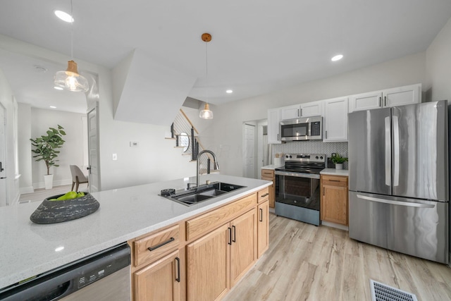 kitchen with decorative light fixtures, tasteful backsplash, sink, white cabinets, and stainless steel appliances