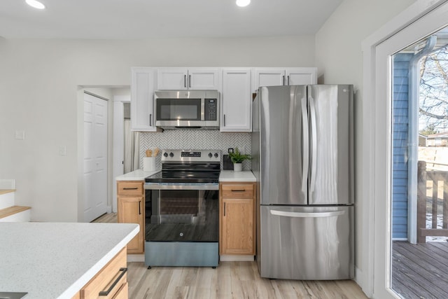 kitchen featuring light brown cabinetry, tasteful backsplash, stainless steel appliances, light hardwood / wood-style floors, and white cabinets