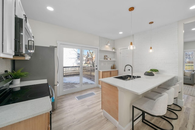 kitchen with appliances with stainless steel finishes, decorative light fixtures, sink, a kitchen breakfast bar, and kitchen peninsula