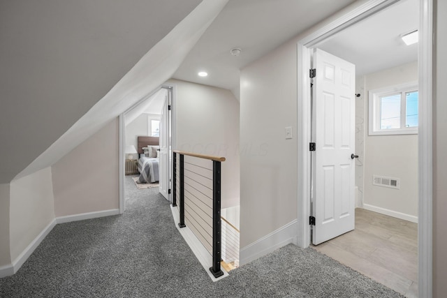 hallway with vaulted ceiling and carpet flooring