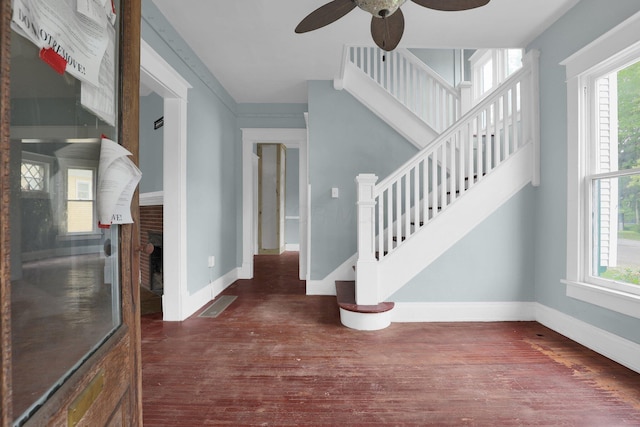 entryway featuring ceiling fan, dark wood-type flooring, and a brick fireplace