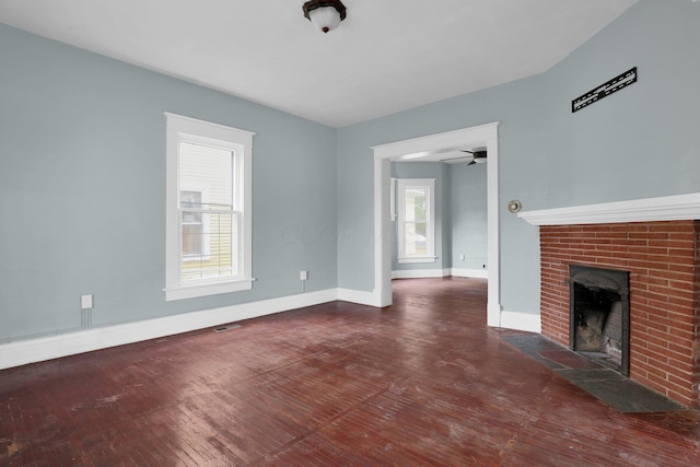 unfurnished living room with a brick fireplace and dark wood-type flooring