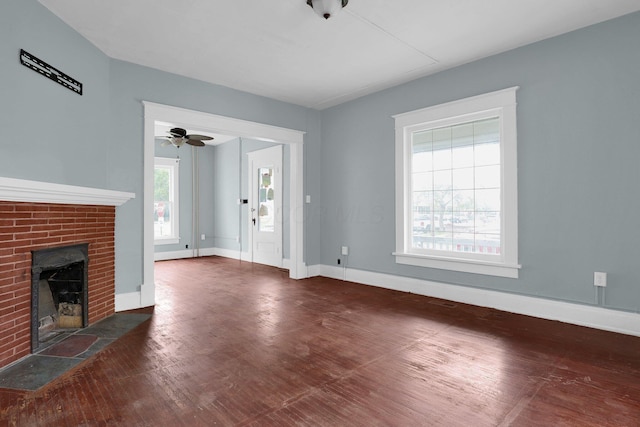 unfurnished living room featuring a brick fireplace, plenty of natural light, and dark wood-type flooring