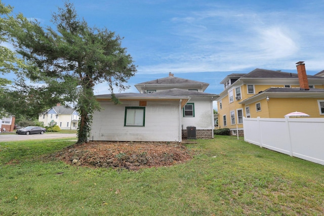 back of house with central air condition unit and a yard