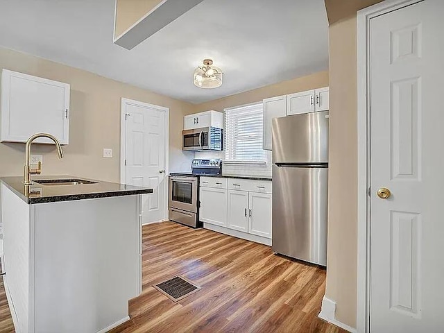 kitchen with white cabinets, light hardwood / wood-style floors, appliances with stainless steel finishes, and sink