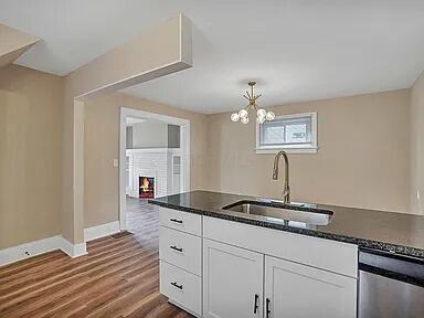 kitchen with dishwasher, white cabinetry, a fireplace, sink, and dark hardwood / wood-style floors