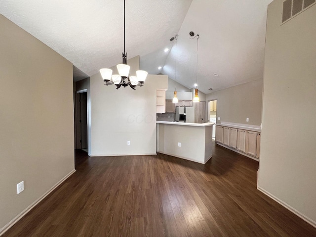 kitchen featuring hanging light fixtures, dark wood-type flooring, stainless steel fridge, and vaulted ceiling