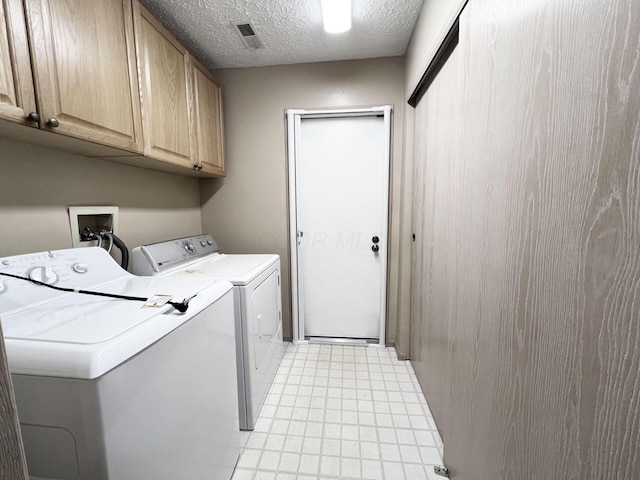 laundry area featuring cabinets, separate washer and dryer, and a textured ceiling