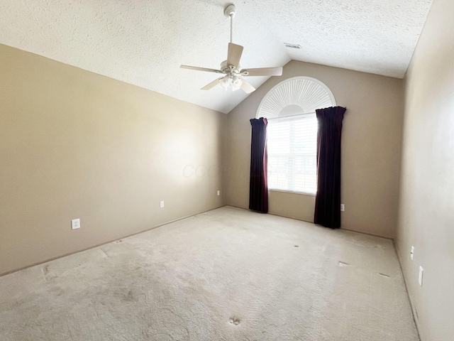 spare room featuring vaulted ceiling, light colored carpet, a textured ceiling, and ceiling fan