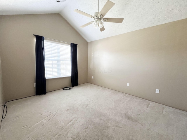 carpeted empty room featuring a textured ceiling, vaulted ceiling, and ceiling fan