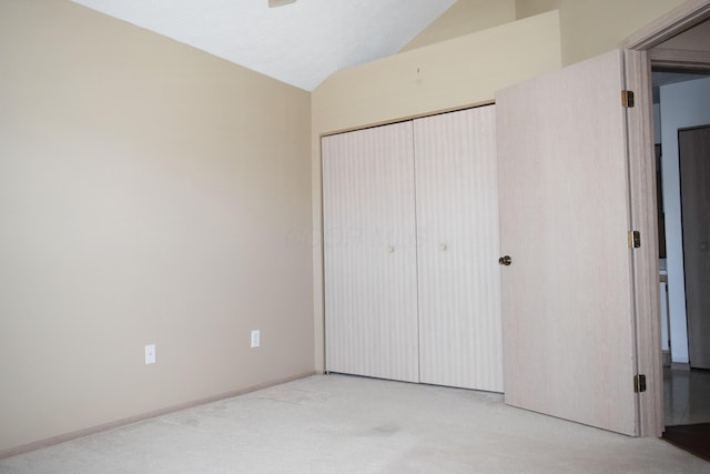 unfurnished bedroom with a closet, vaulted ceiling, and light carpet