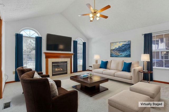 living room featuring ceiling fan, lofted ceiling, a healthy amount of sunlight, and a tiled fireplace