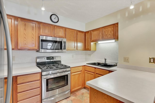 kitchen featuring appliances with stainless steel finishes, kitchen peninsula, sink, and a textured ceiling