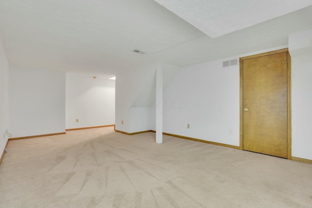 unfurnished room with light carpet and a textured ceiling