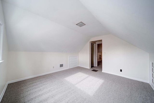 bonus room with vaulted ceiling and carpet floors