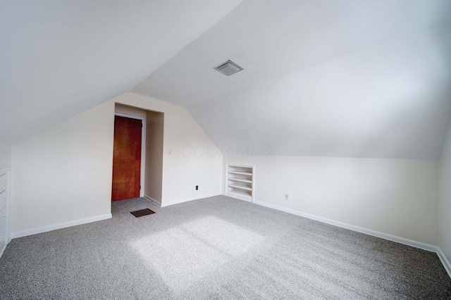 bonus room featuring built in shelves, carpet, and lofted ceiling