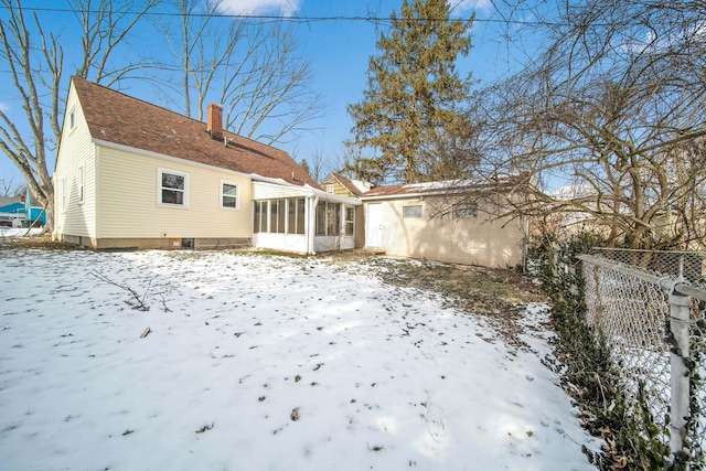 snow covered house featuring a sunroom