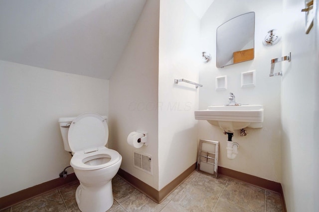 bathroom with sink, toilet, and vaulted ceiling