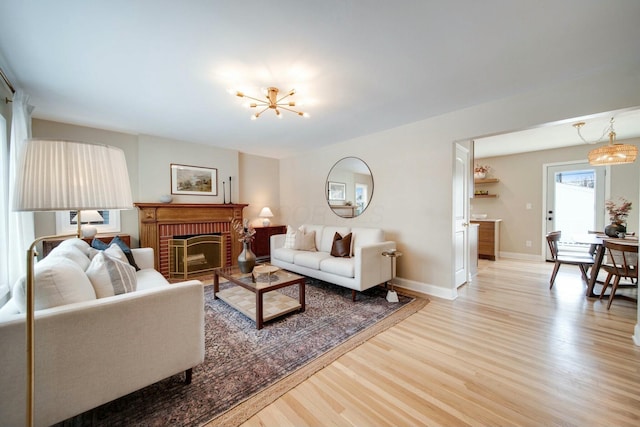 living room featuring a fireplace, a chandelier, and light wood-type flooring