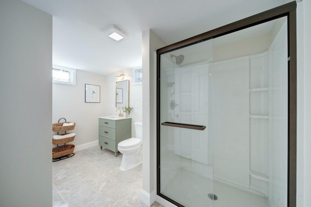 bathroom featuring vanity, a shower with shower door, and toilet