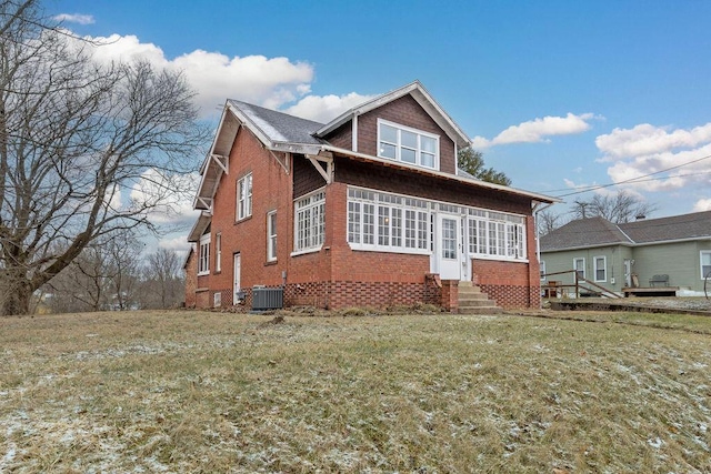 exterior space with entry steps, brick siding, a yard, and central air condition unit