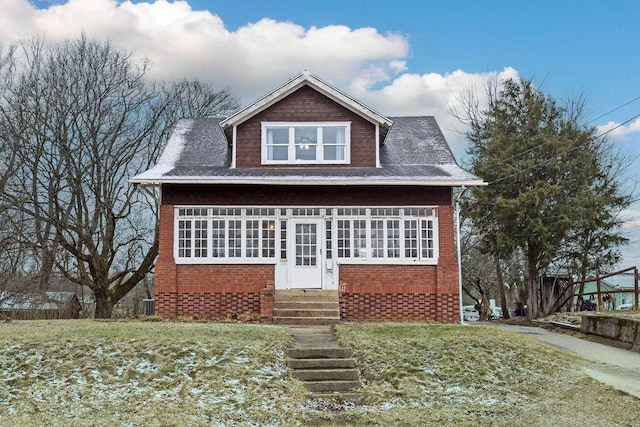 view of front of home with entry steps, brick siding, a front lawn, and central air condition unit