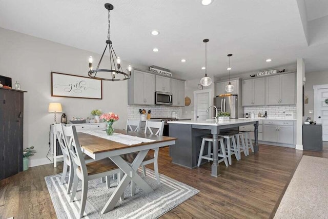 dining space featuring sink, a chandelier, and dark hardwood / wood-style floors