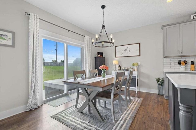 dining space featuring a textured ceiling, a chandelier, and dark hardwood / wood-style flooring