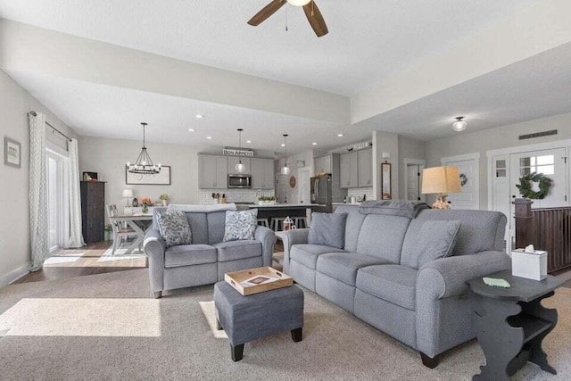 living room featuring ceiling fan with notable chandelier