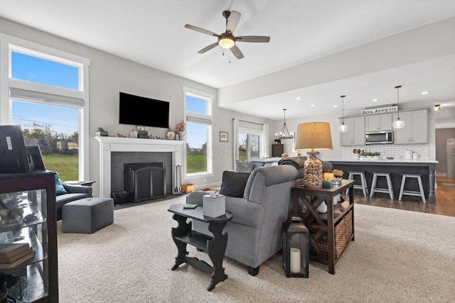 living room featuring ceiling fan with notable chandelier and a tiled fireplace