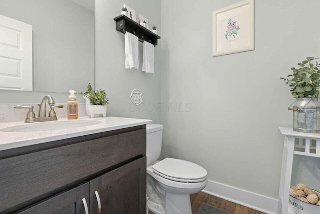 bathroom with hardwood / wood-style floors, toilet, and vanity