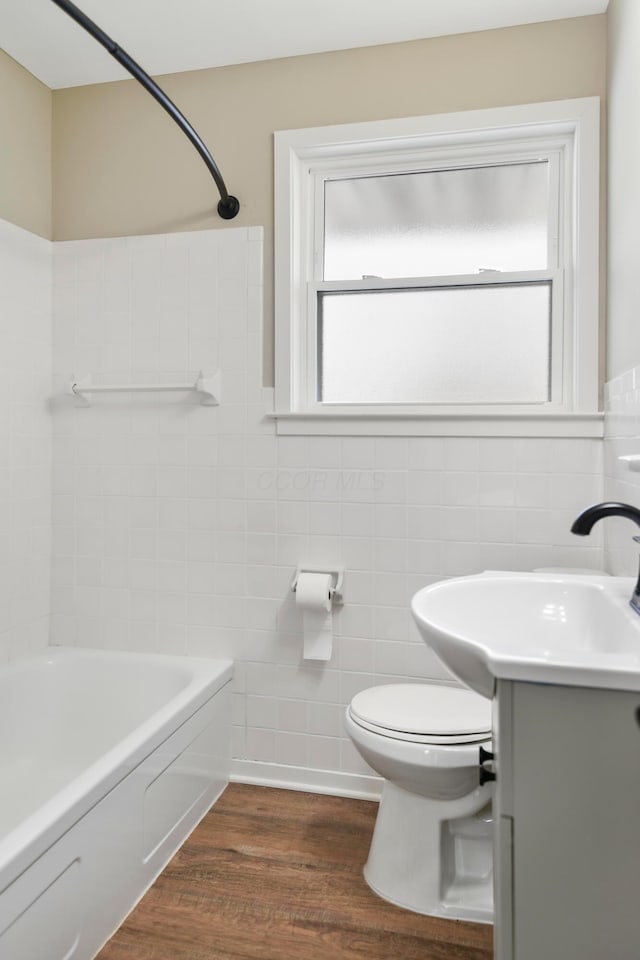 full bathroom featuring tub / shower combination, hardwood / wood-style floors, vanity, tile walls, and toilet