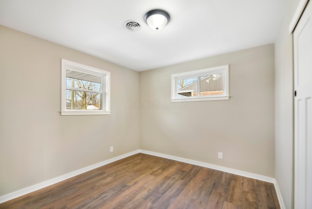 empty room with dark hardwood / wood-style floors and a wealth of natural light