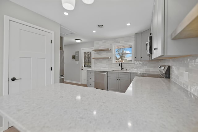 kitchen with sink, backsplash, appliances with stainless steel finishes, and gray cabinets