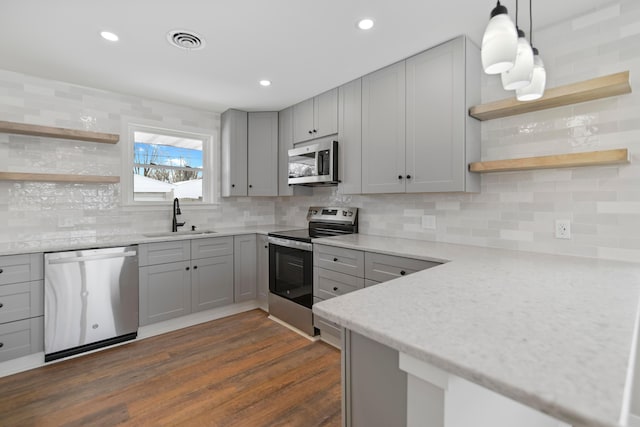 kitchen with pendant lighting, stainless steel appliances, decorative backsplash, sink, and gray cabinetry