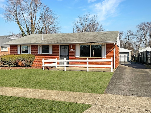 single story home featuring brick siding, a shingled roof, a detached garage, a fenced front yard, and an outbuilding