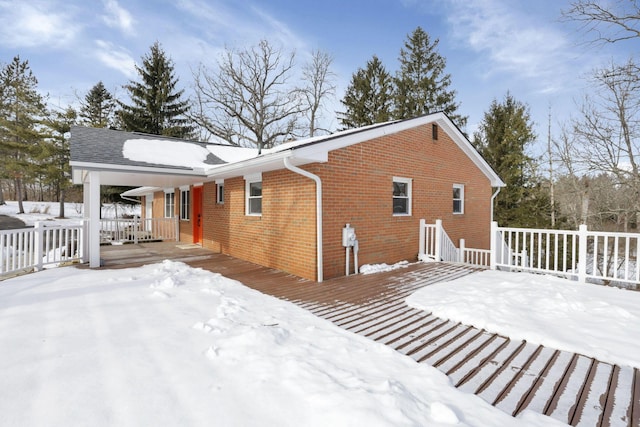 snow covered back of property with a deck