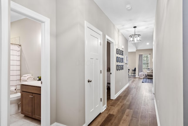 hallway with a notable chandelier and light wood-type flooring