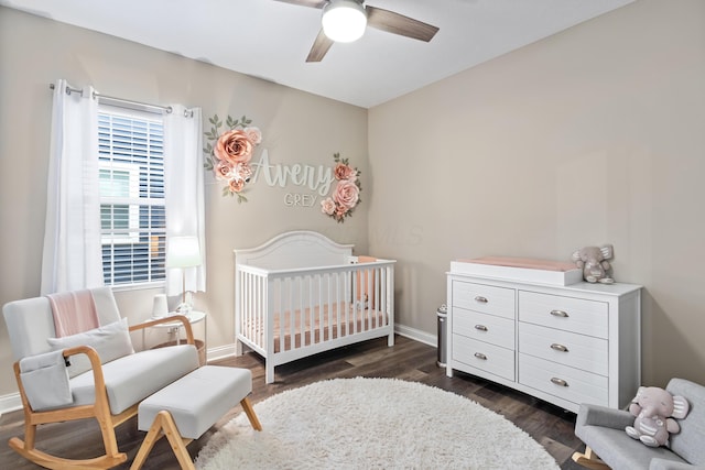 bedroom featuring ceiling fan, dark hardwood / wood-style floors, and a crib