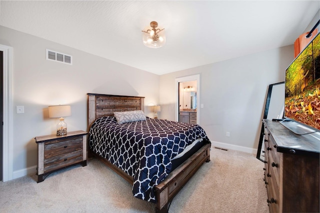 bedroom with connected bathroom and light carpet