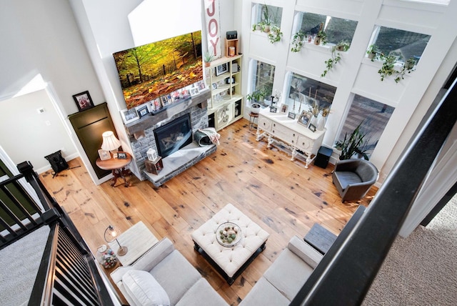 living room featuring a high ceiling, a stone fireplace, and hardwood / wood-style floors