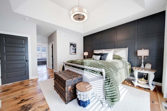 bedroom with a tray ceiling and light hardwood / wood-style floors