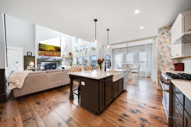 kitchen with appliances with stainless steel finishes, an island with sink, sink, white cabinets, and a kitchen bar