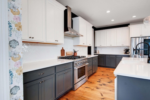 kitchen featuring gray cabinetry, wall chimney exhaust hood, white cabinets, and appliances with stainless steel finishes