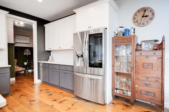 kitchen featuring gray cabinetry, stainless steel fridge, white cabinets, and light hardwood / wood-style flooring